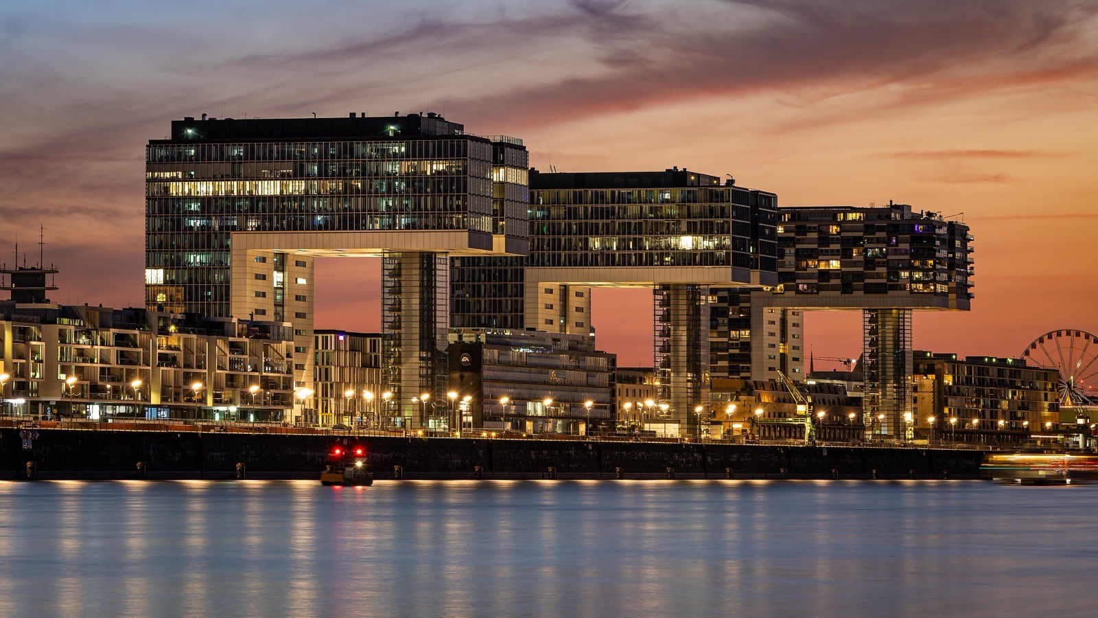 Die drei Kranhäuser im Kölner Rheinauhafen bei Sonnenuntergang, gespiegelt im Rhein