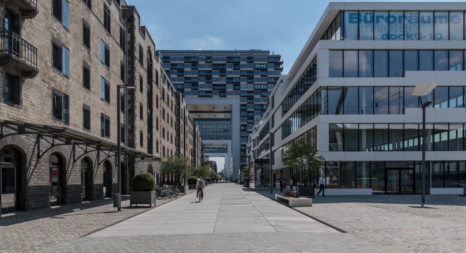 Die Straße Im Zollhafen im Kölner Rheinauhafen, links der historische Speicher, rechts moderne Bürogebäude, im Hintergrund ein Kranhaus