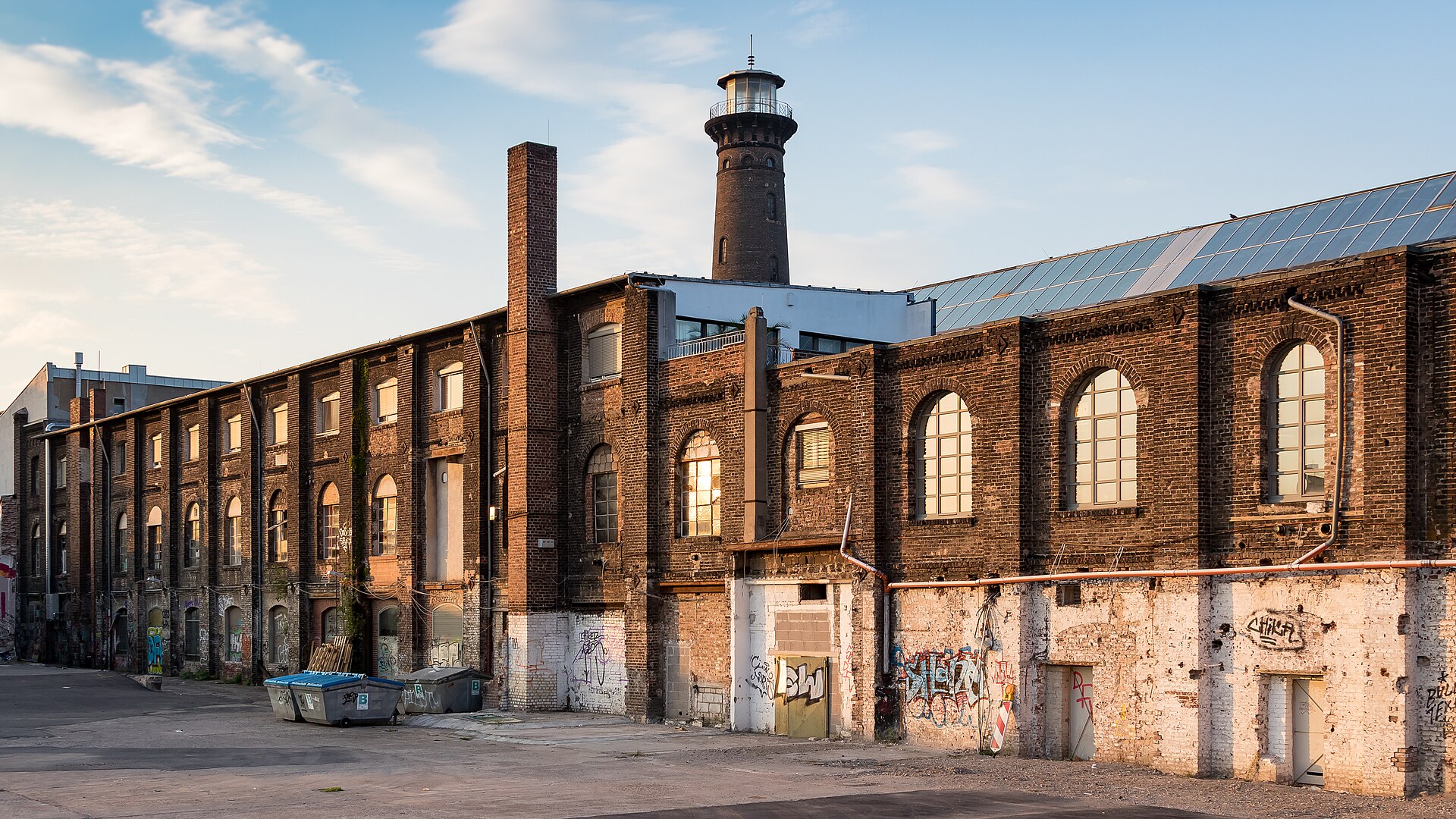 Backsteingebäude auf dem Helios-Gelände in Köln-Ehrenfeld im Abendlicht, dahinter der Heliosturm