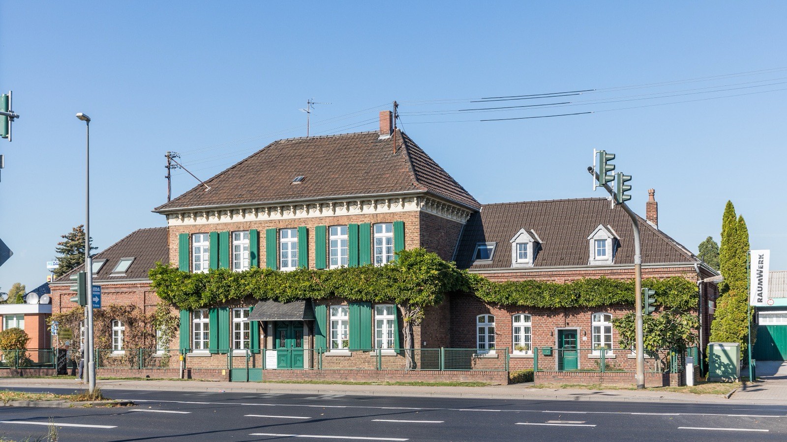 Der Kemmerlingshof an der Dürener Straße in Köln-Junkersdorf, ein Backsteinhof mit grünen Fensterläden und Weinbewuchs
