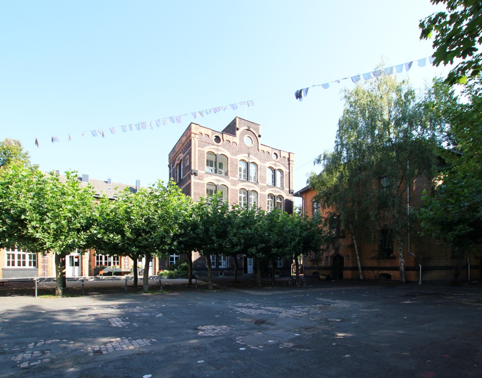 Innenhof der Alten Feuerwache in Köln-Neustadt-Nord, ein Backsteinbau mit Bäumen davor