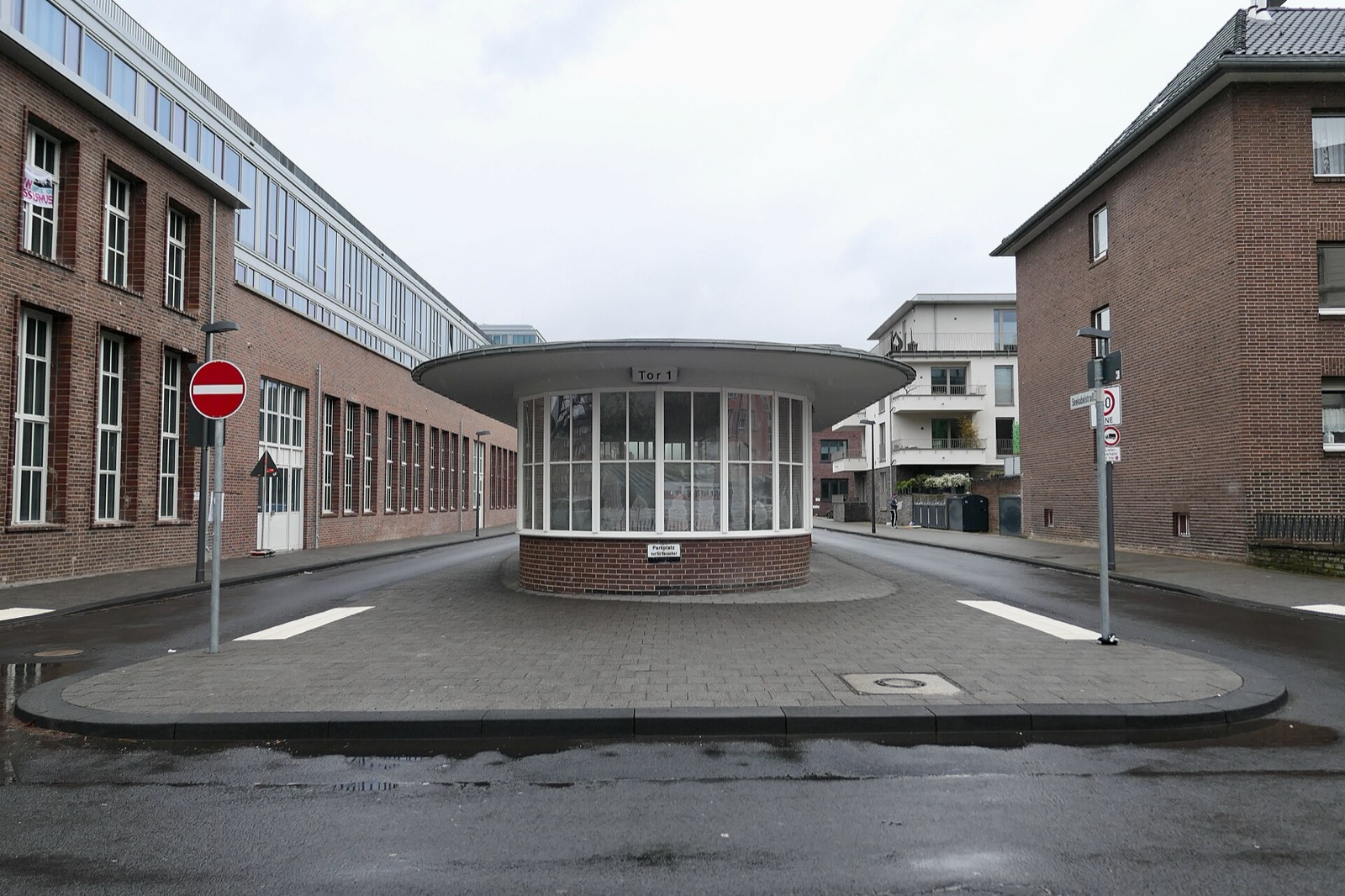 Tor 1 des ehemaligen Clouth-Geländes in Köln-Nippes: historisches Pförtnerhaus zwischen Backstein-Industriebau links und moderner Wohnbebauung rechts
