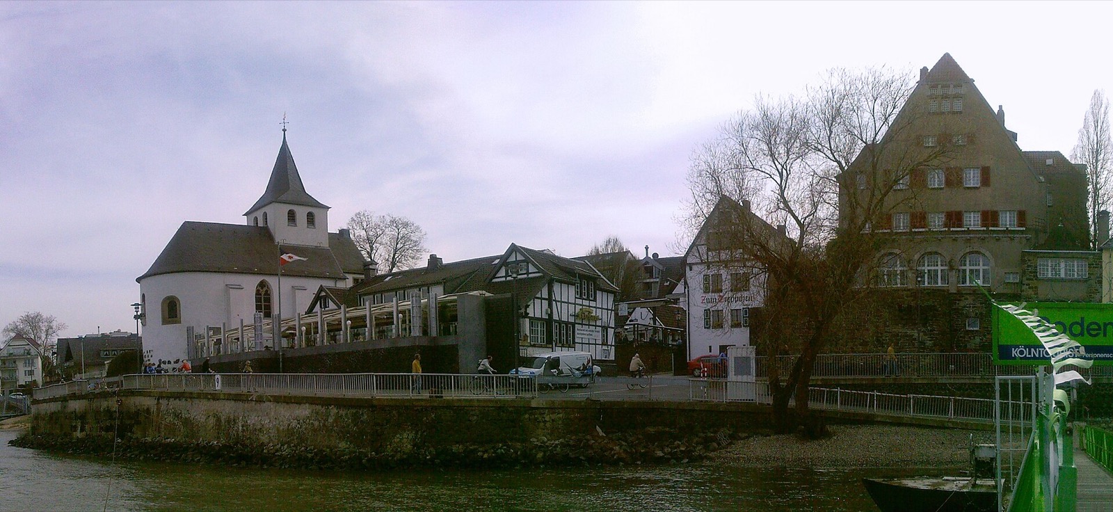 Alt-Rodenkirchen vom Rhein aus gesehen: die alte Kirche, Fachwerkhäuser und ein Gründerzeitbau am Ufer