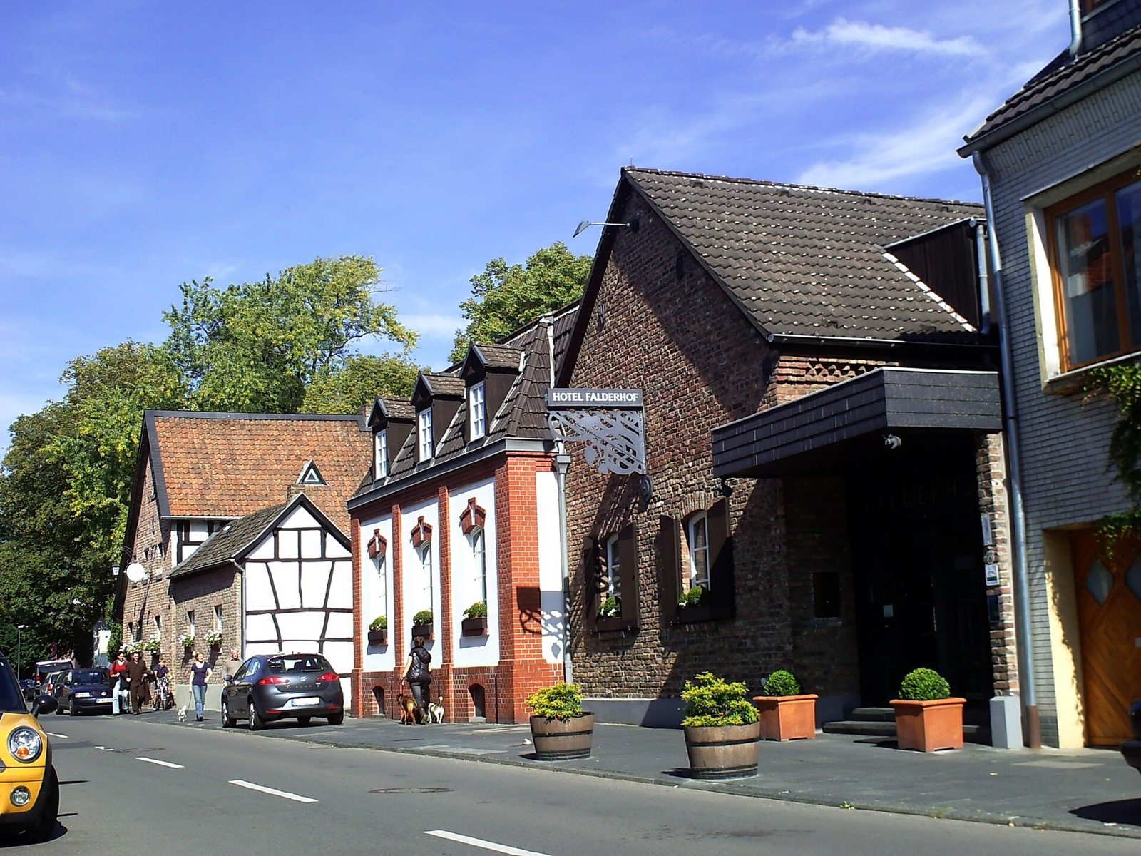 Der Falderhof in Köln-Sürth: historische Hofanlage aus Backstein und Fachwerk an der Straße, davor Fußgänger
