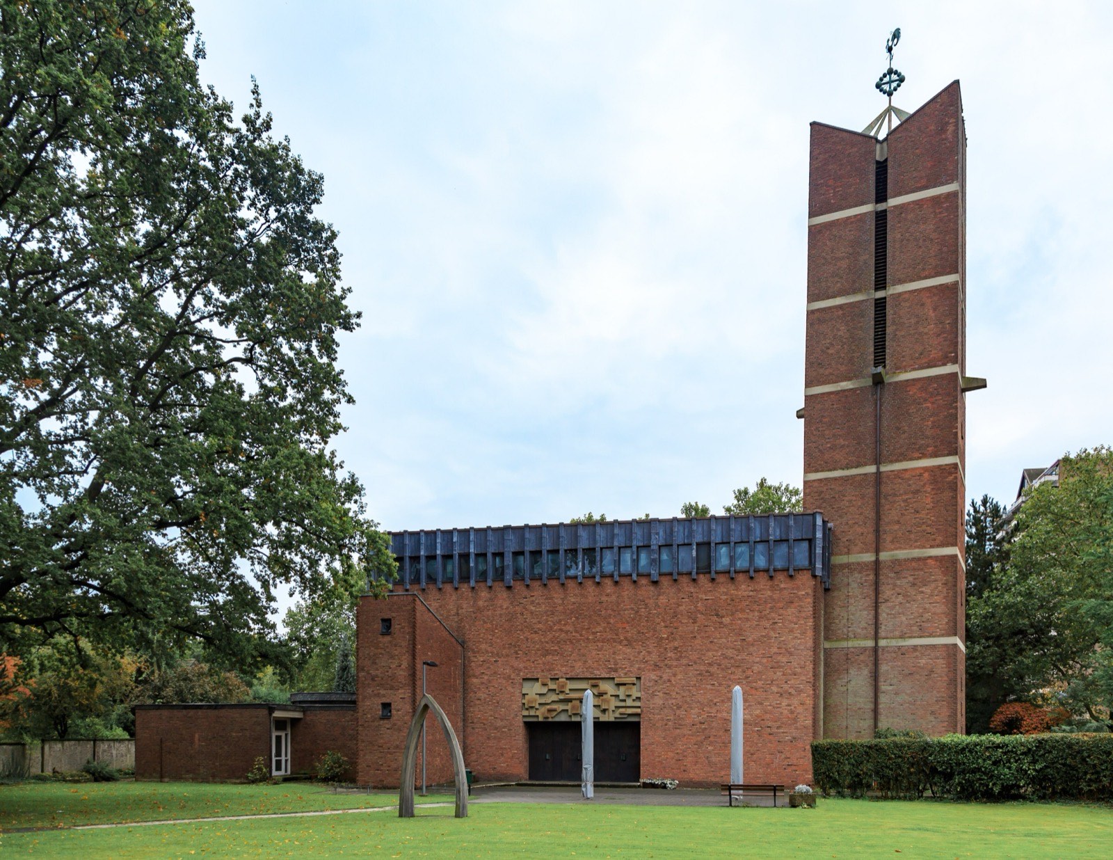 Die Heilig-Geist-Kirche in Köln-Weiden, ein Backsteinbau der Nachkriegszeit mit hohem Turm auf einer Rasenfläche