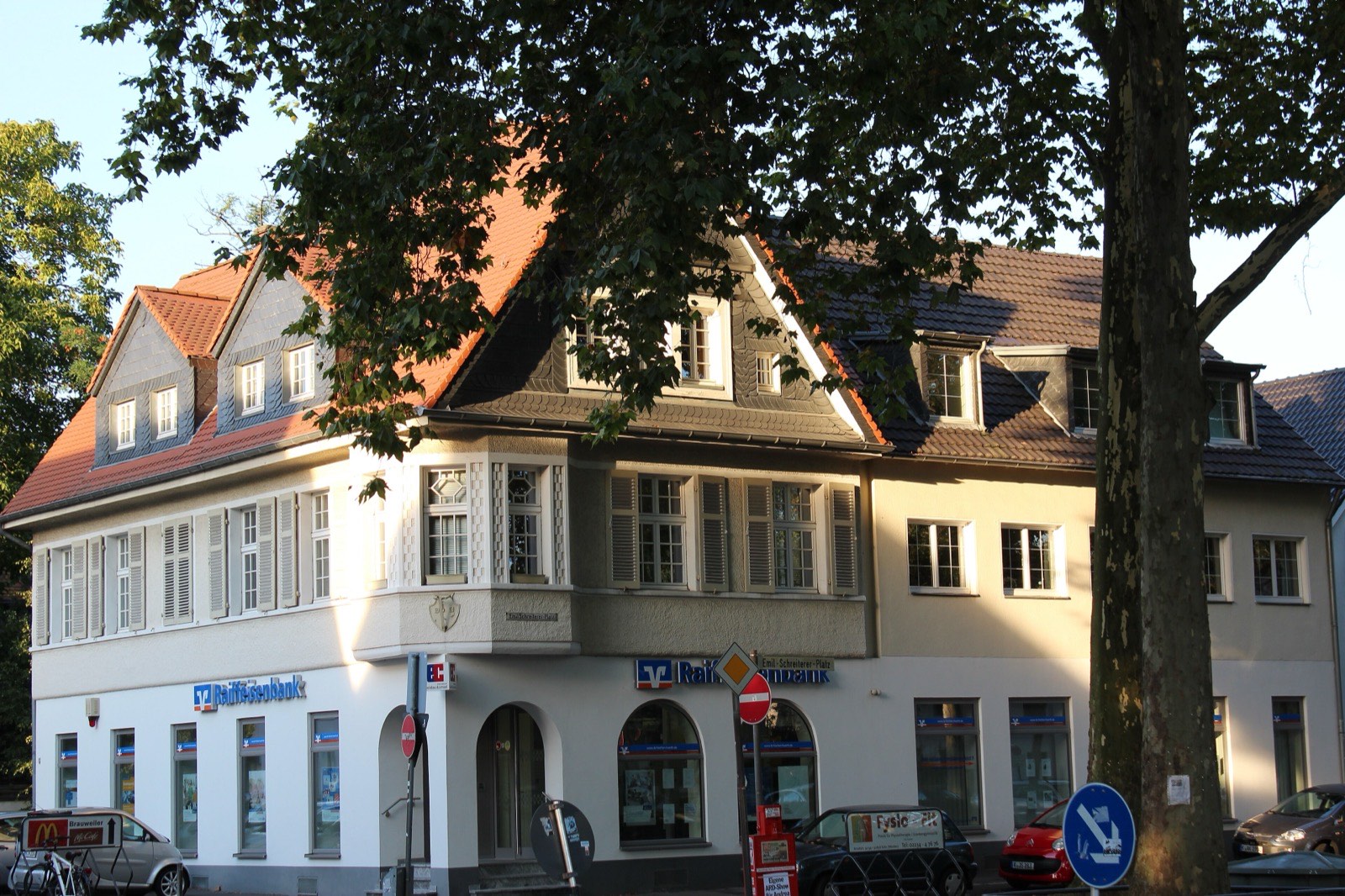 Historisches Wohn- und Geschäftshaus am Ortskern von Köln-Weiden im Abendlicht, umgeben von alten Bäumen